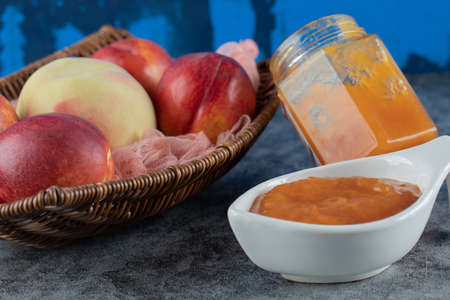 Peach and apples in a wooden basket on a piece of pink towelの写真素材