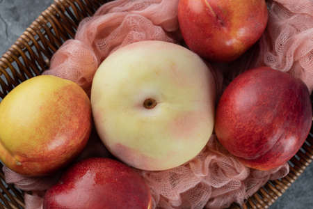 Wooden fruit basket with apples and red peaches