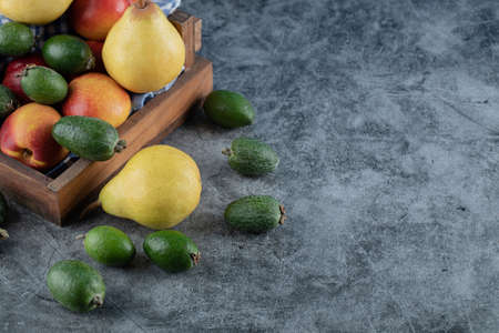 A wooden fruit tray full of pears, feijoas and peaches