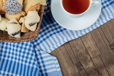 Chocolate sesame cookies in a wooden basket with a cup of earl grey teaの写真素材