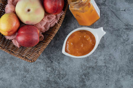 Peach and apples in a wooden basket on a piece of pink towelの写真素材