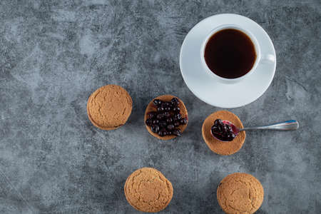 Oatmeal cookies with blackcurrant berries confiture served with a cup of tea