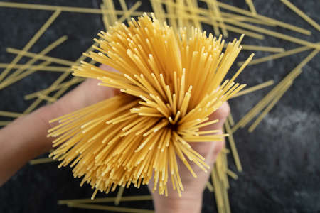 Woman hands holding spaghetti on dark backgroundの写真素材