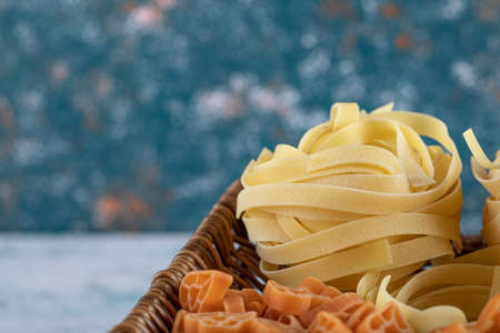 Close up view of assortment of raw pasta in wooden basketの写真素材