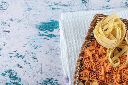 Assortment of raw pasta in wooden basketの写真素材