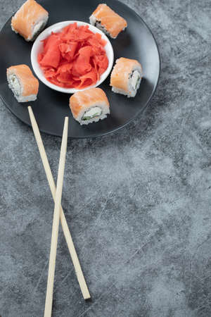 Salmon rolls in a black plate with red marinated gingerの写真素材