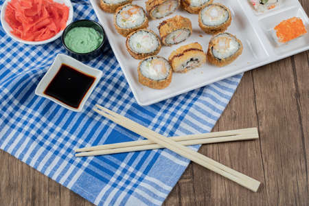 Fried hot rolls in a wooden platter with soy sauce, wasabi and ginger