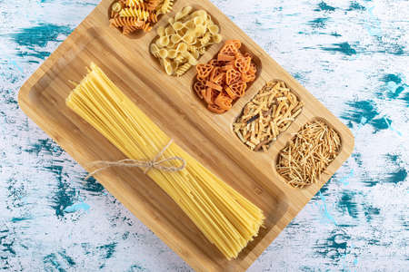 Assortment of uncooked pasta placed on wooden plateの写真素材