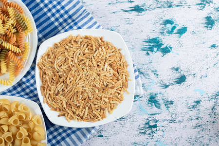 Variety of dry pasta on white platesの写真素材