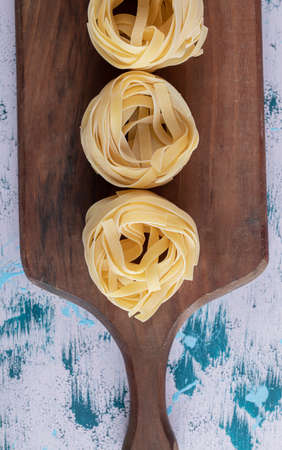 Raw tagliatelle nests on wooden boardの写真素材