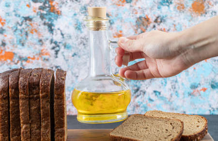 Hand holding a bottle of oil on a colorful background