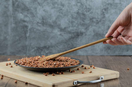 Female hand holding wooden spoon of red beans