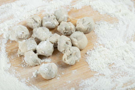 Raw dumplings with flour on a wooden boardの写真素材