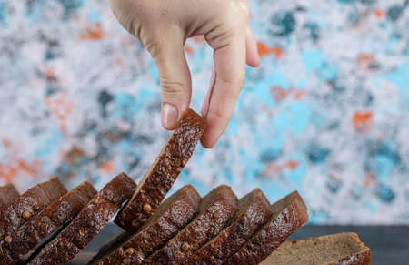 Female hand holding brown bread slice on colorful backgroundの写真素材