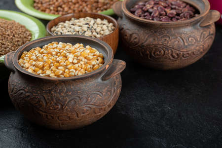 Different kinds of bean seeds, lentil, peas in dishes on a dark backgroundの写真素材
