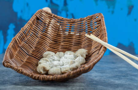 Uncooked dumplings in wooden basket with chopsticksの写真素材
