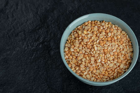 A blue plate with uncooked popcorn on a dark backgroundの写真素材