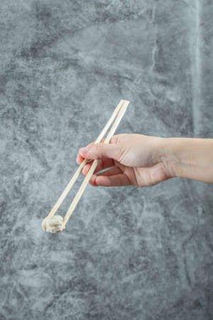 Female hand holding food dumpling with chopsticksの写真素材