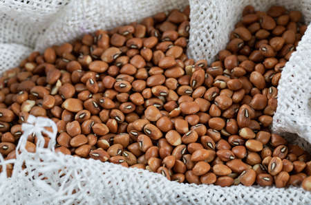 Brown unprepared kidney beans on a wooden basket