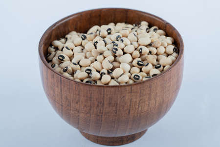 A small wooden bowl full of raw white peas