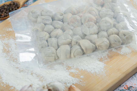 Pocket of raw dumplings with flour on a wooden board