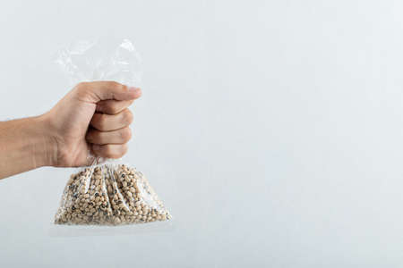 Male hand holding a stack of raw brown dried kidney beansの写真素材