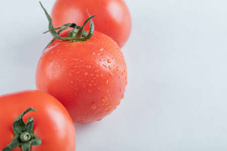 Three whole fresh tomatoes on a white backgroundの写真素材