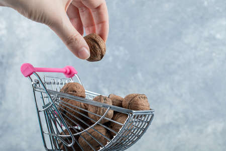 Hand holding a healthy walnut on a gray backgroundの写真素材