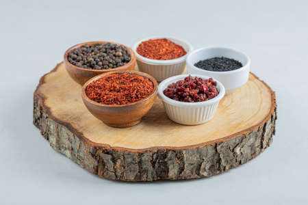 Many bowls of spices on a wooden board