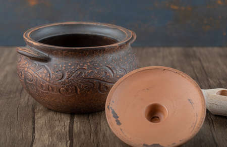 Ancient pot with a wooden spoon on a wooden tableの写真素材