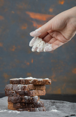 Female hand pouring a pinch of flour on breadの写真素材