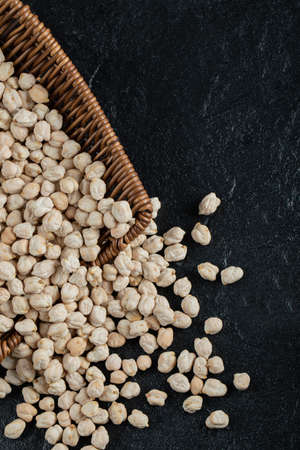 Whole dry white peas in wicker basket on a dark backgroundの写真素材