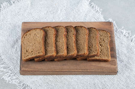 A wooden cutting board with slices of brown bread
