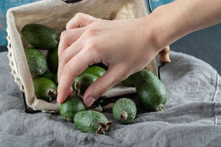 Hand taking a feijoa from basket on a gray tableclothの写真素材