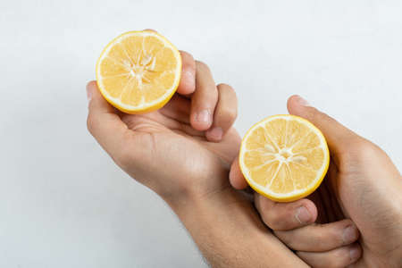 Hand holding a slice of lemon on a white backgroundの写真素材