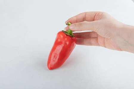 A whole fresh red pepper on a gray background