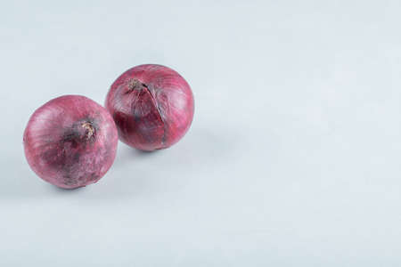 Two whole purple onion on a gray backgroundの写真素材