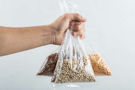 Man hand holding bags with raw beans on a white backgroundの写真素材