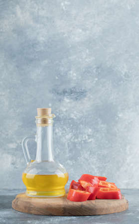 Sliced of sweet bell red pepper with a glass bottle of oil on a wooden boardの写真素材