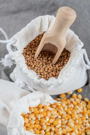 A white sack full of corn grains and buckwheat on a gray backgroundの写真素材