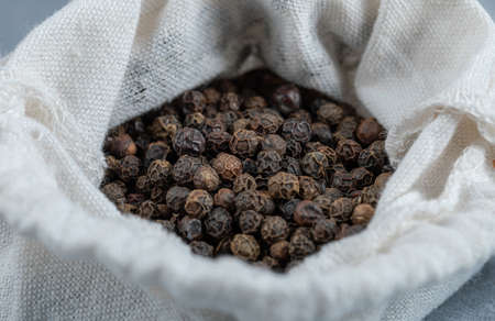A white sack full of dried pepper on a gray background