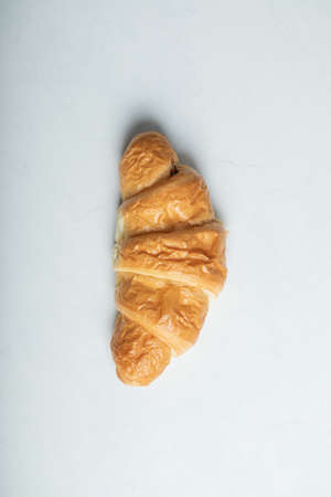 One whole fresh delicious croissant on a white backgroundの写真素材