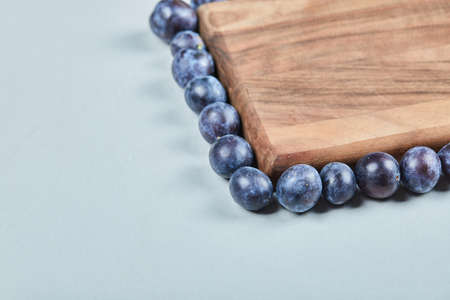 Group of fresh plums around the wooden board