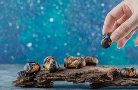 Female hand holding a piece of fried chestnutの写真素材