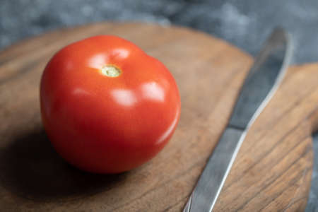 Fresh juicy tomato with knife on a gray backgroundの写真素材