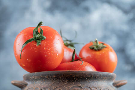 An ancient pot with fresh tomatoes on a gray backgroundの写真素材