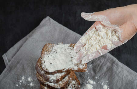 Slices of brown bread with flour on a gray tablecloth
