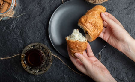 Woman hands holding a fresh croissant on a dark plate. High quality photoの写真素材