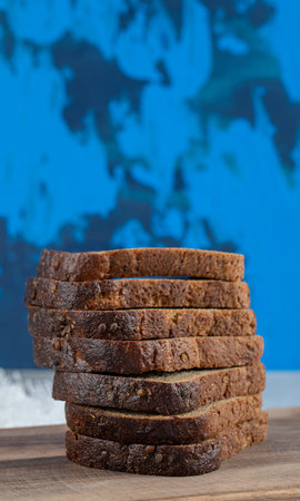 A wooden cutting board with slices of brown bread . High quality photo