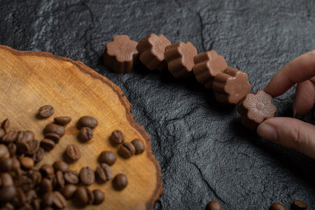Hand taking chocolate candies on a dark backgroundの写真素材